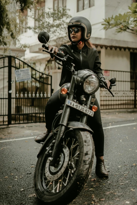 a man wearing black sits on his motorcycle on the side of the road