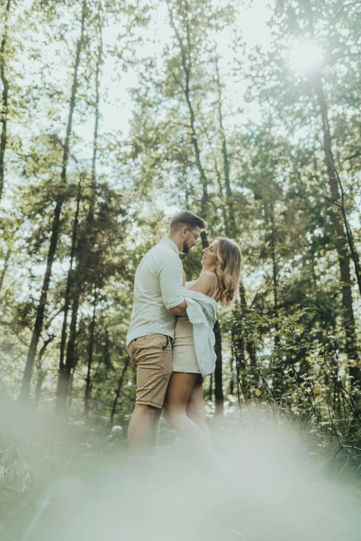 couple emcing in forest surrounded by trees