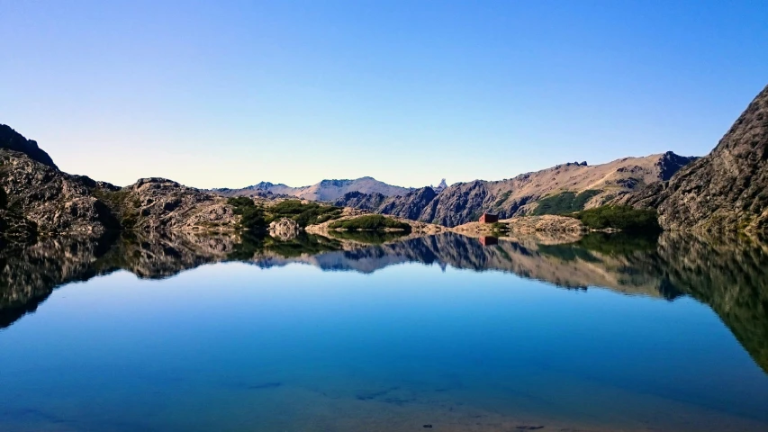 a small lake surrounded by mountains is very clear