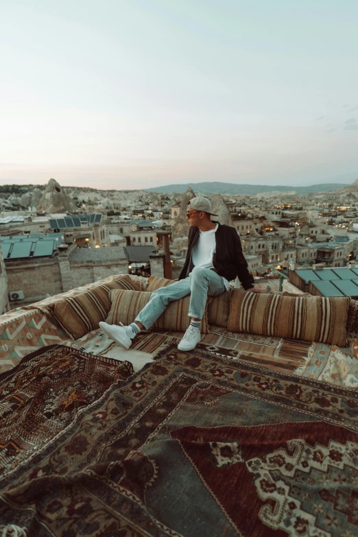 a man sits on a colorfully - decorated rug in the middle of an old city