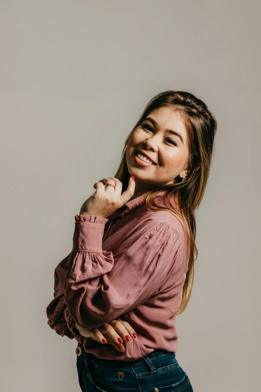 a smiling girl is posing with her hand on her chin