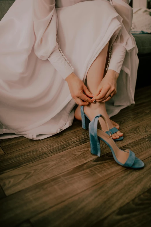 a bride putting her heels on by the bed