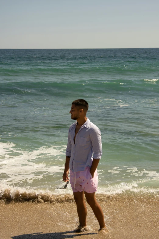 a man is standing on the beach with his surfboard