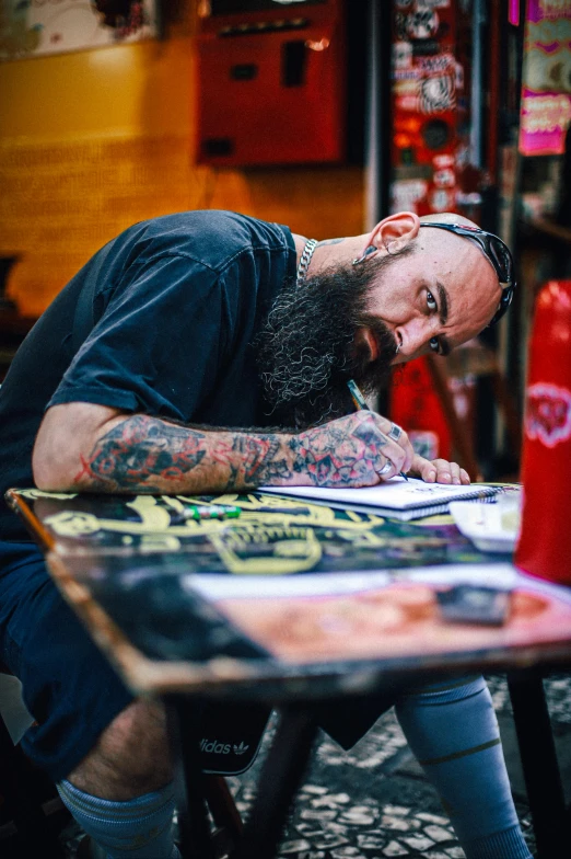 a man with a beard in blue shirt writing