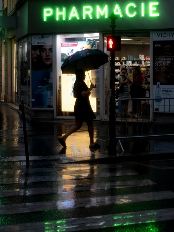 people walk past pharmacy as it is raining