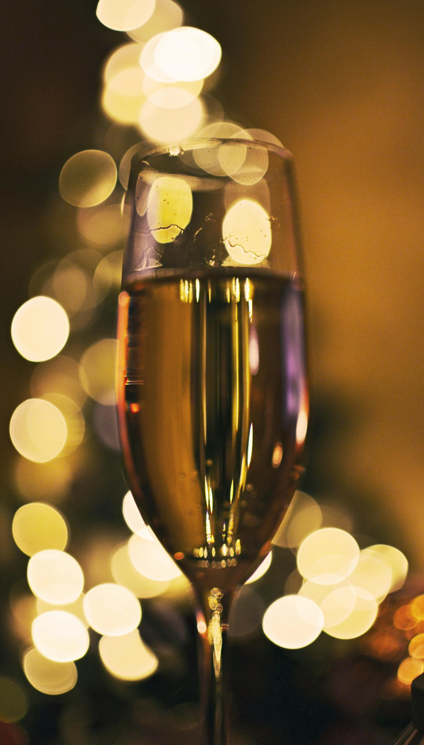 a glass of champagne on a table with lights in the background