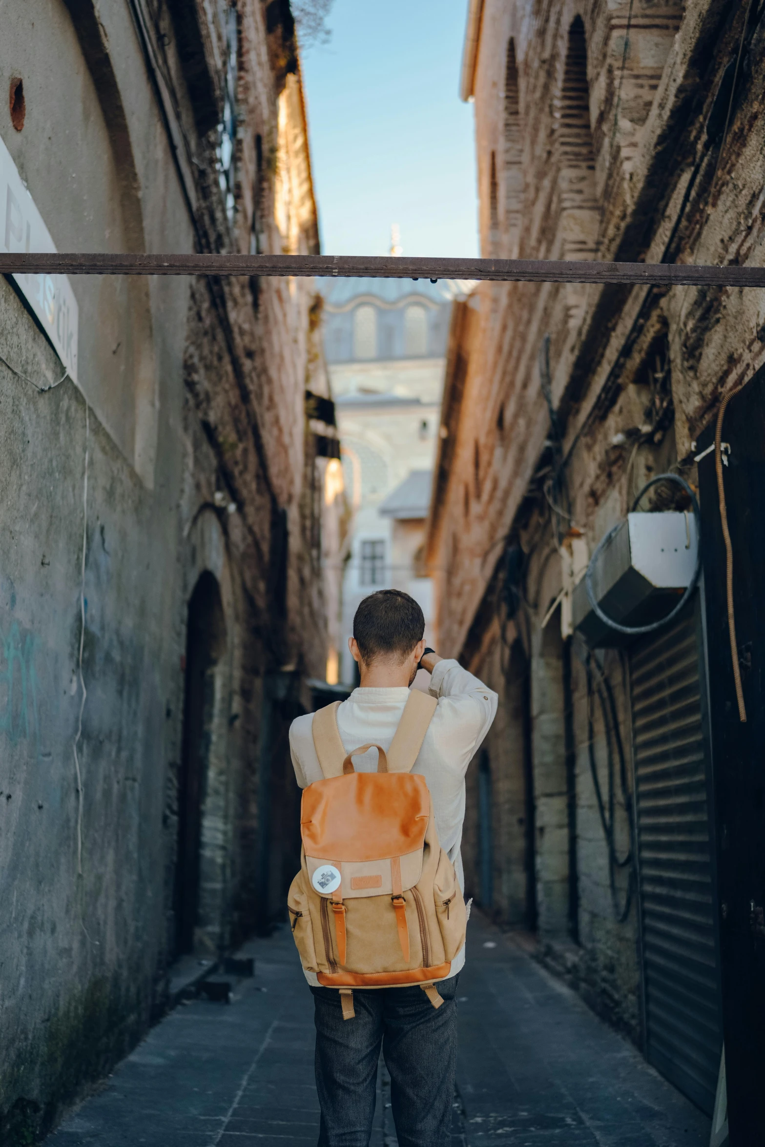 a man is standing in an alleyway with a backpack