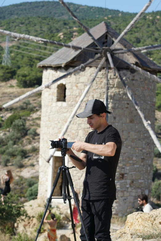 a man holding a camera next to a rock tower