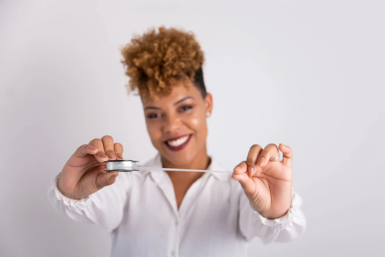 woman holding an object in her hand while standing against a white background