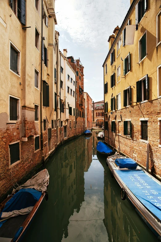 two rows of buildings and parked boats along the side of a canal