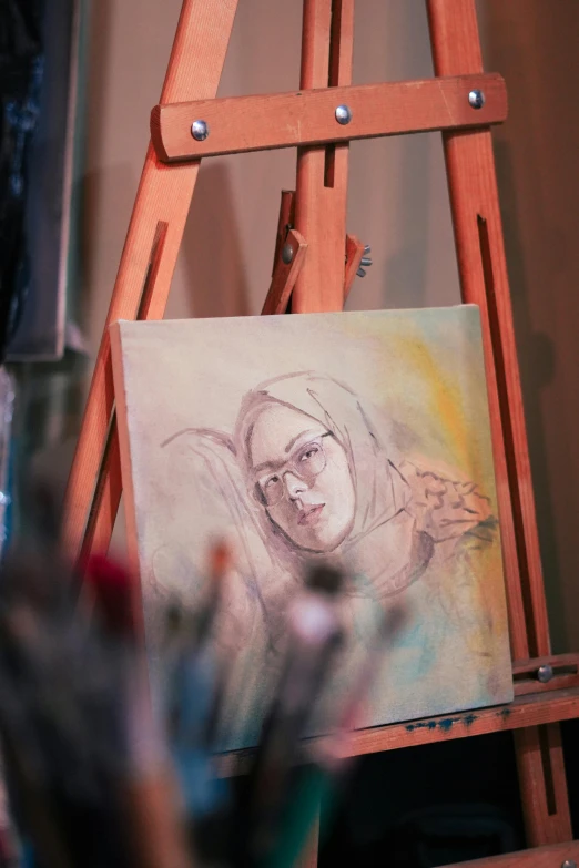 there is a drawing on the easel with a cup of flowers near it