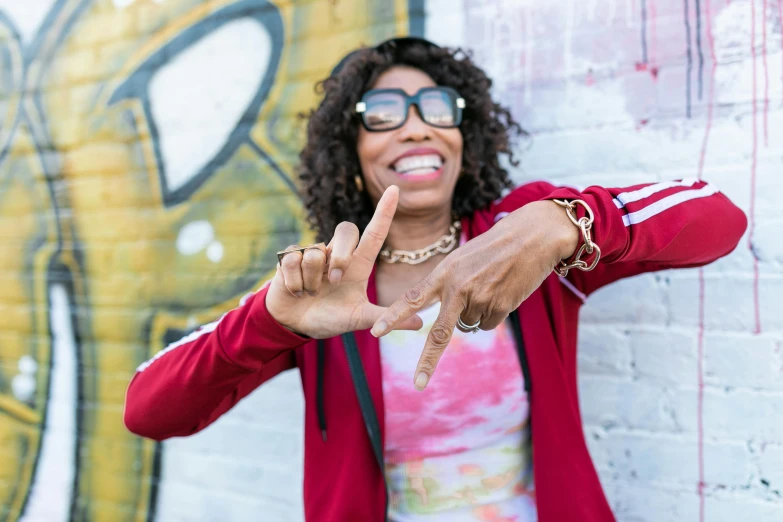 a woman wearing glasses holds up a peace sign