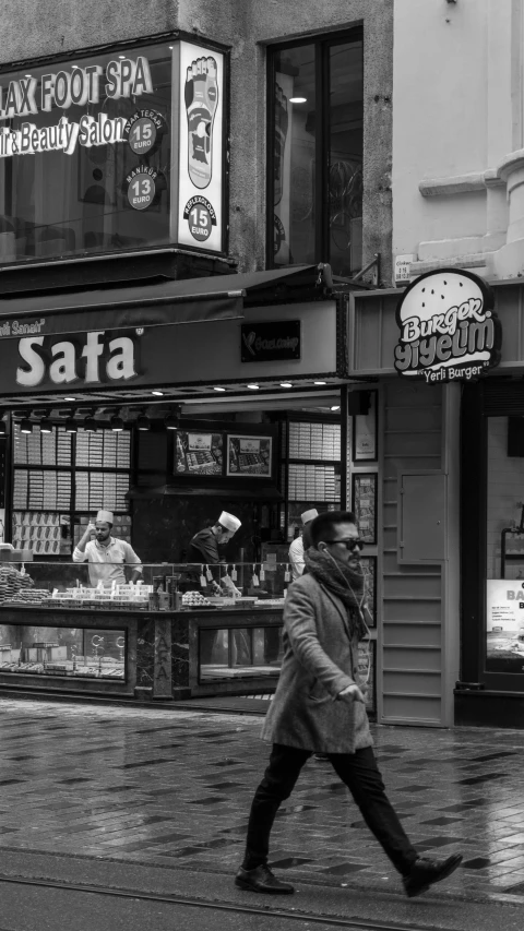 a man walks down the sidewalk past stores