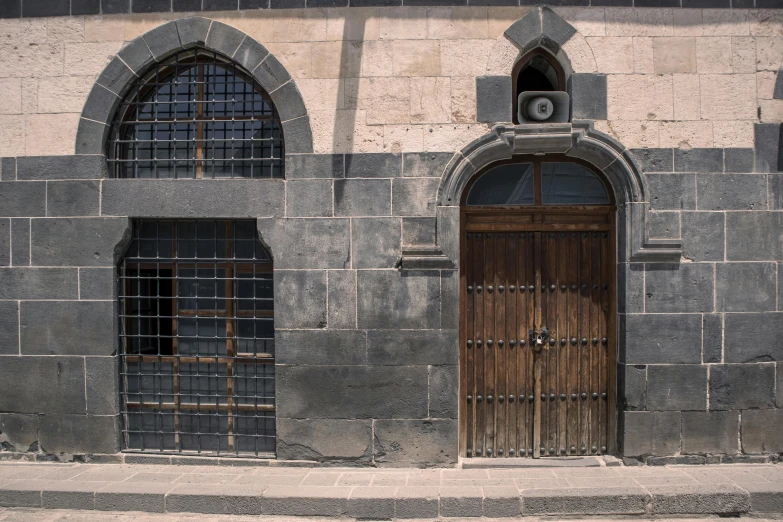 an old building has two wooden doors and arched windows