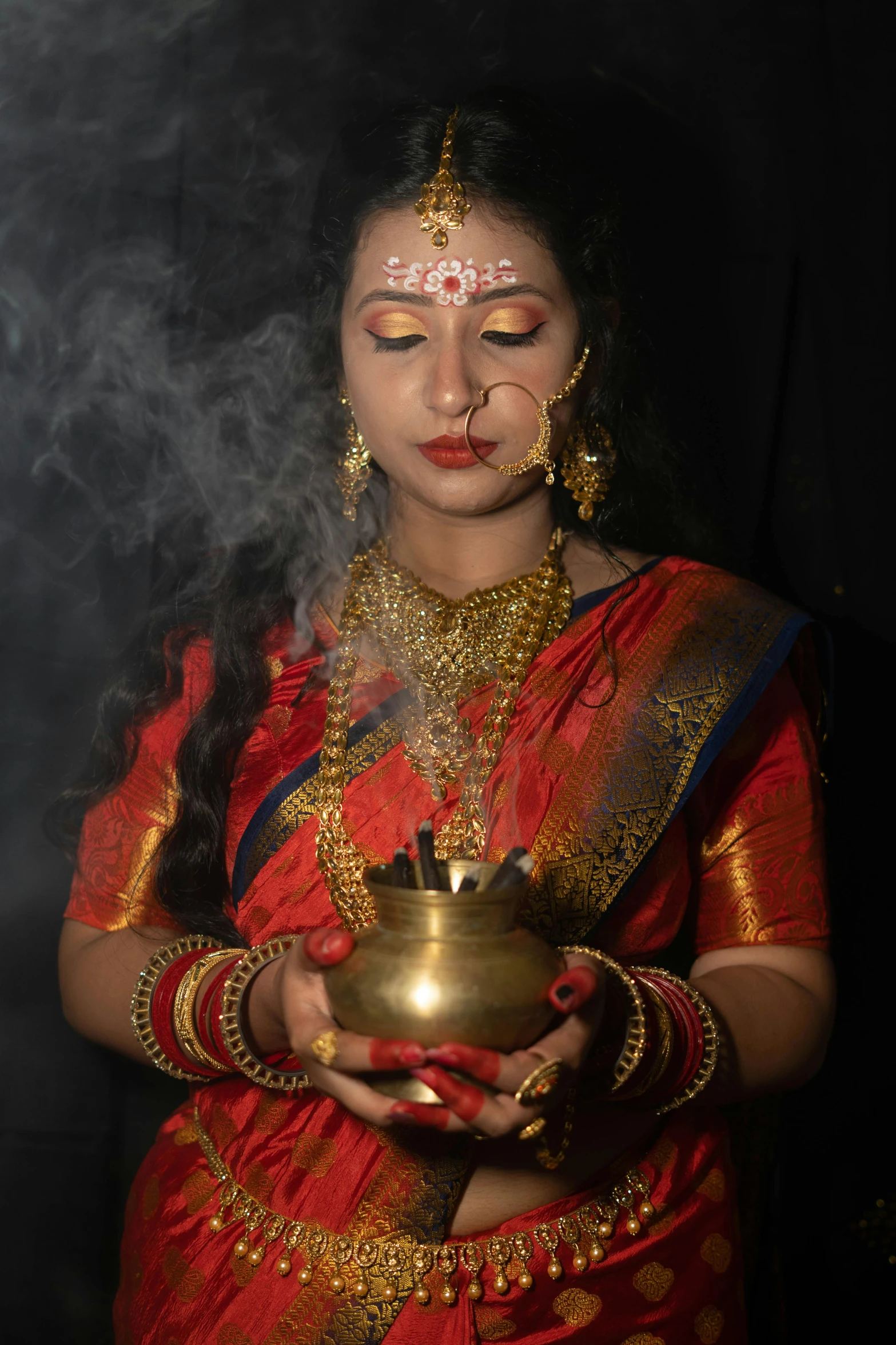 a woman is dressed in indian attire, holding a tea pot