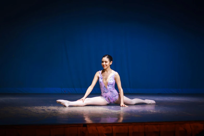 a girl sitting on the floor wearing white and purple leotards