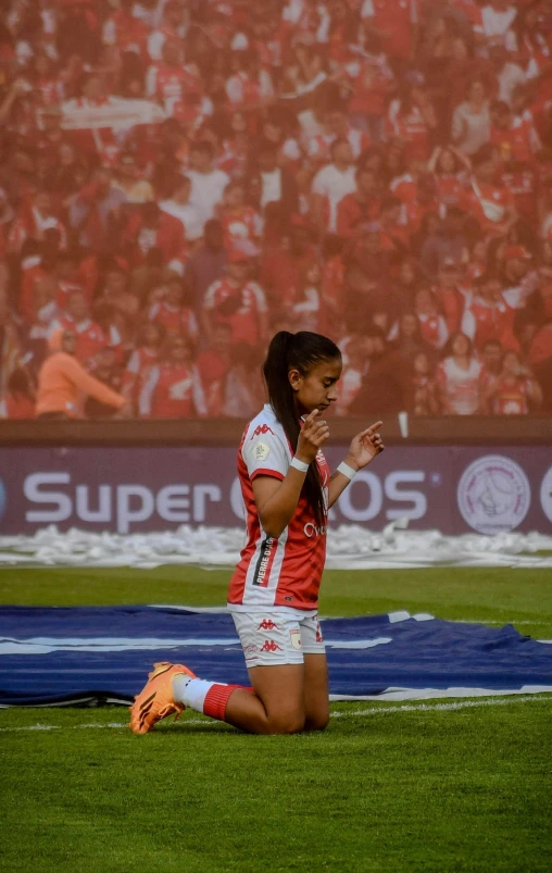 an athlete kneeling on the ground in front of a crowd