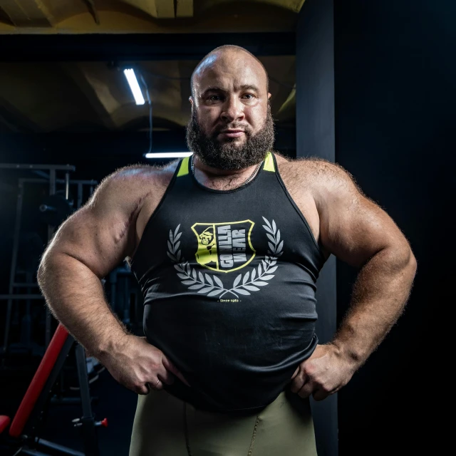 a man with large muscles standing in front of a bar