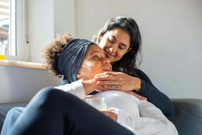 two people are sitting on the couch and one person is using a cellphone