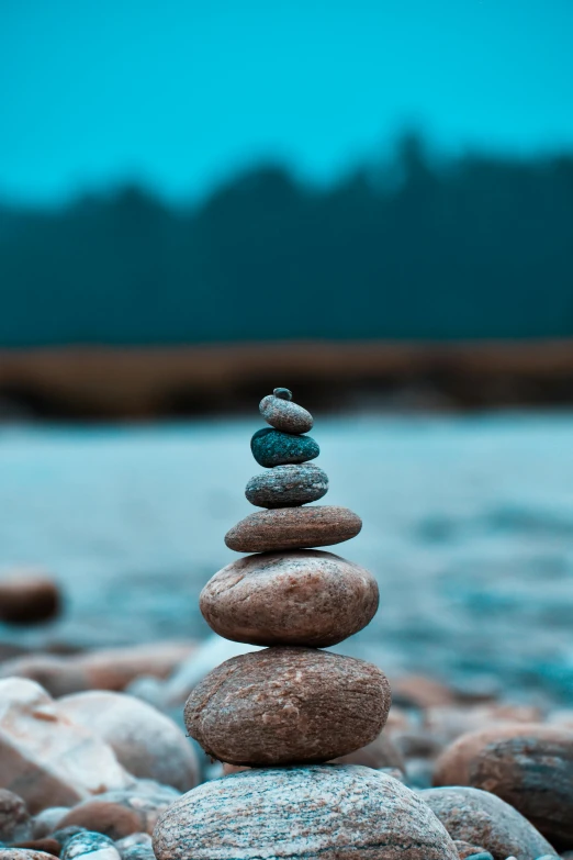 a stack of rocks next to water and some grass