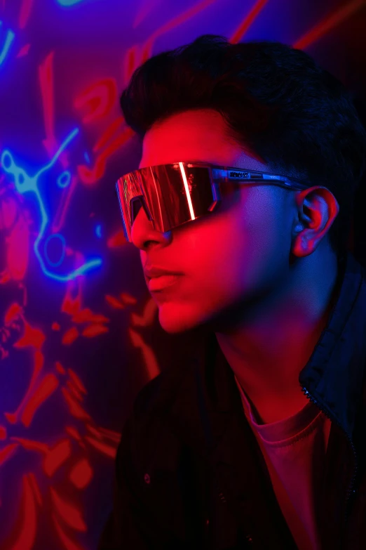 a young man wearing goggles with red light reflecting on his eyes