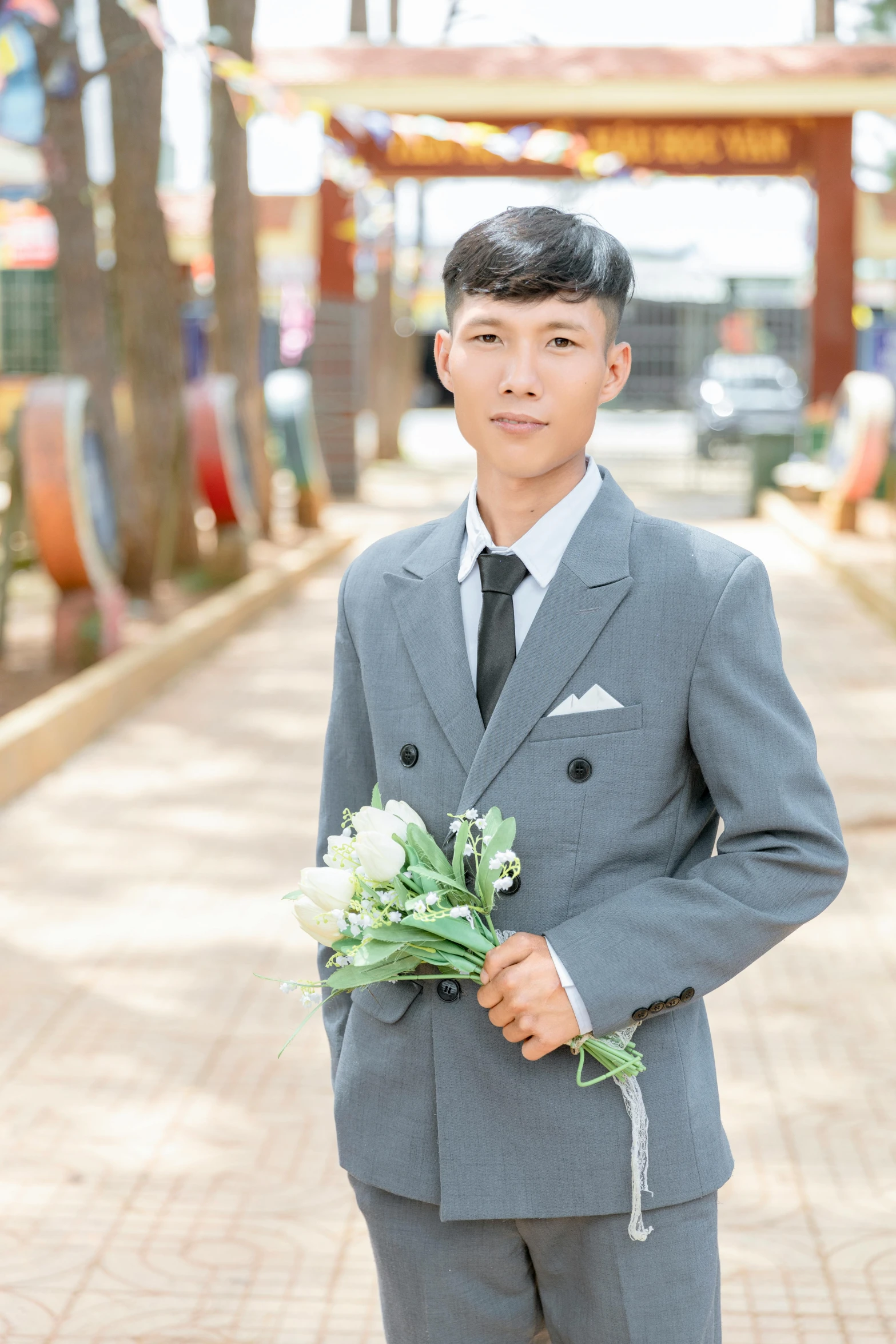 a boy in suit standing next to flowers