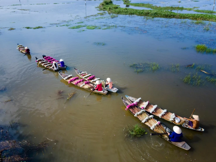 two canoes are tied up to shore with people standing on them