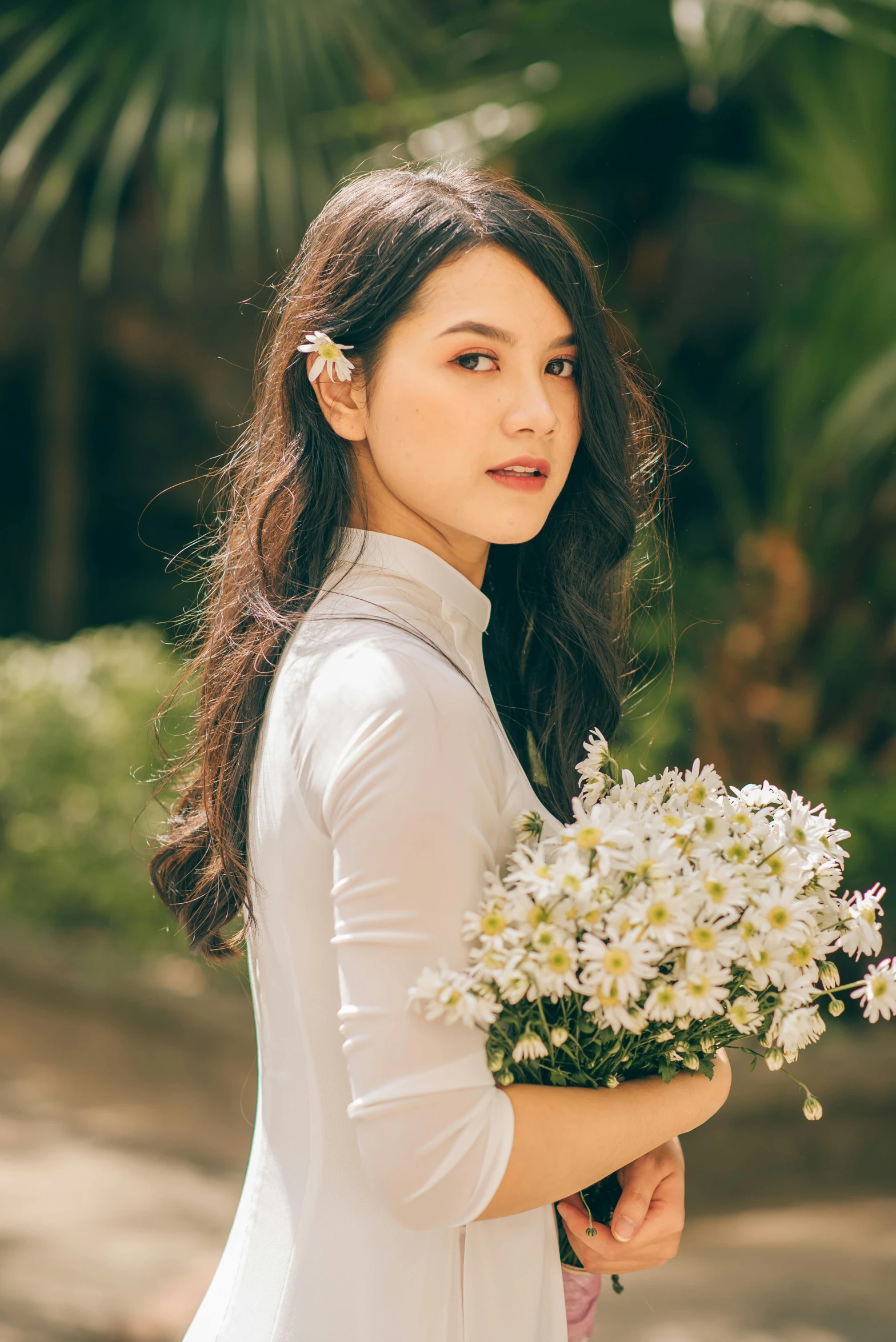 a young woman wearing a white dress is holding flowers