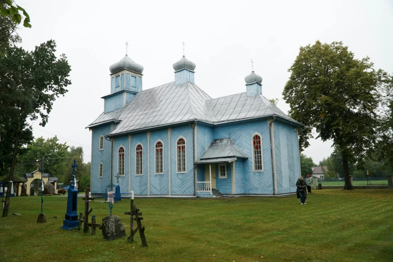 a small blue church with two steeples on it's roof