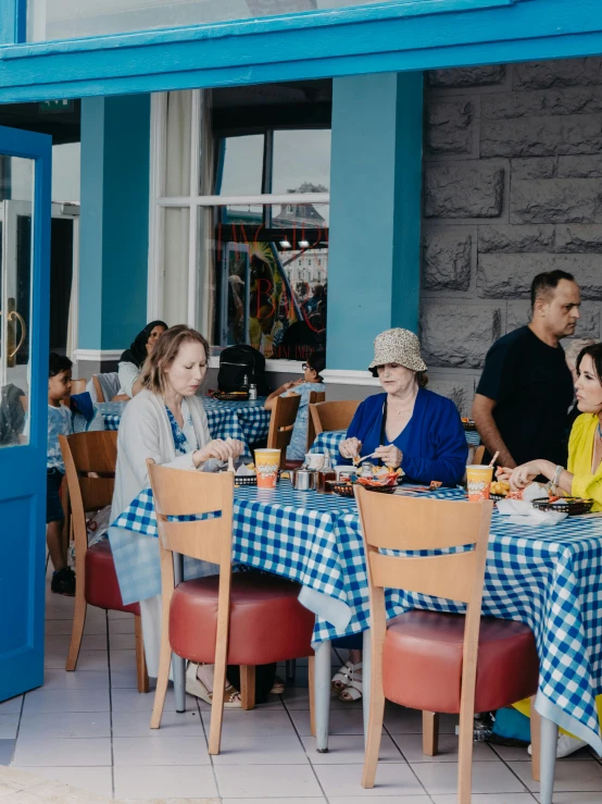 people sit at a small outdoor restaurant table while two other people stand