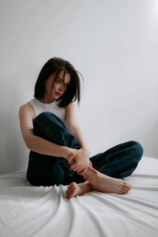 a woman is sitting on the bed tying up her shoe