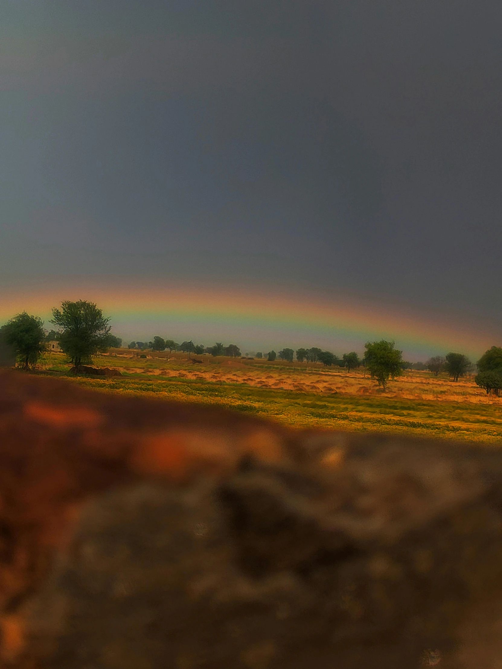 a rainbow over the ground with a rock on it