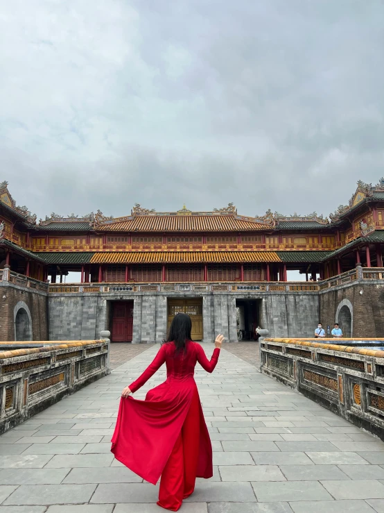 a woman in a red dress standing on a stone walkway