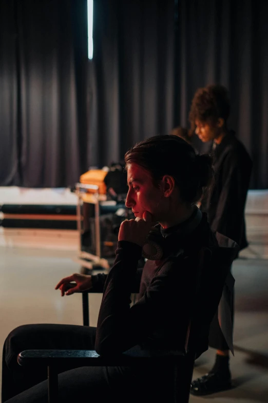 a man sits in a chair while a woman stands and watches