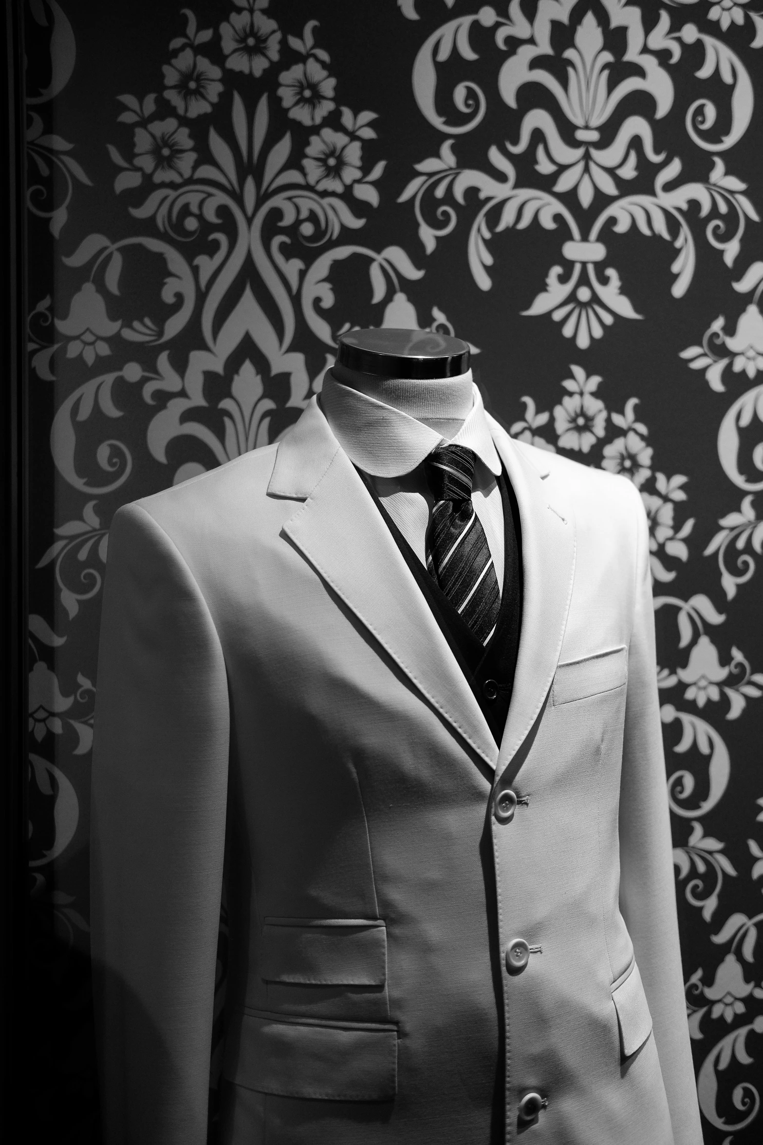 a man's white suit is sitting on a mannequin