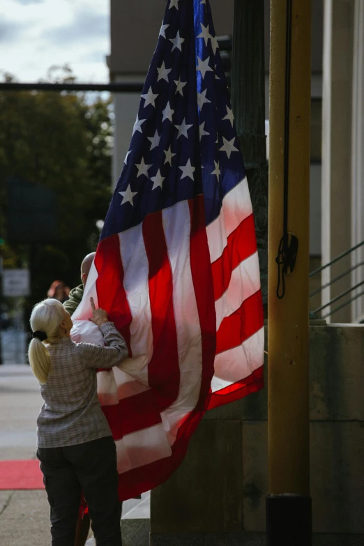 a small child is placing the american flag on a street pole