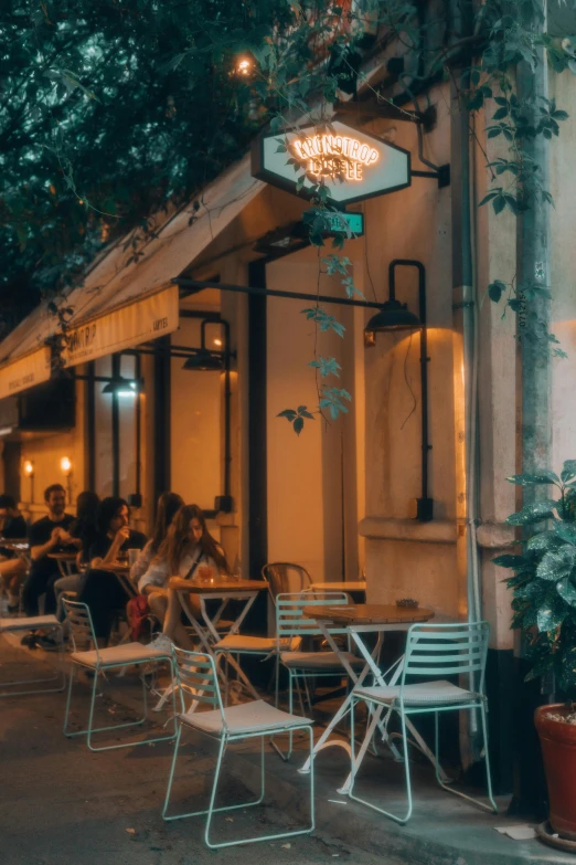 people sitting outside at tables near a building