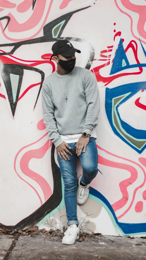 a man that is sitting against a wall with graffiti