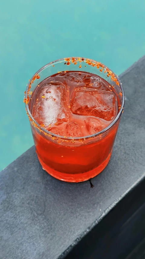 a closeup po of a beverage glass next to a pool