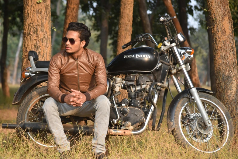 a man sits on his motorcycle in a park