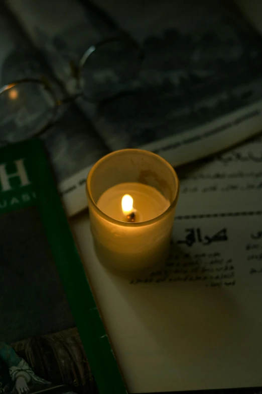 an empty candle sits next to some books