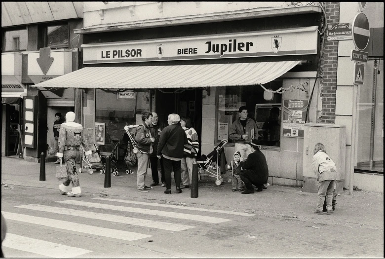 several children are sitting outside of a shop in the street