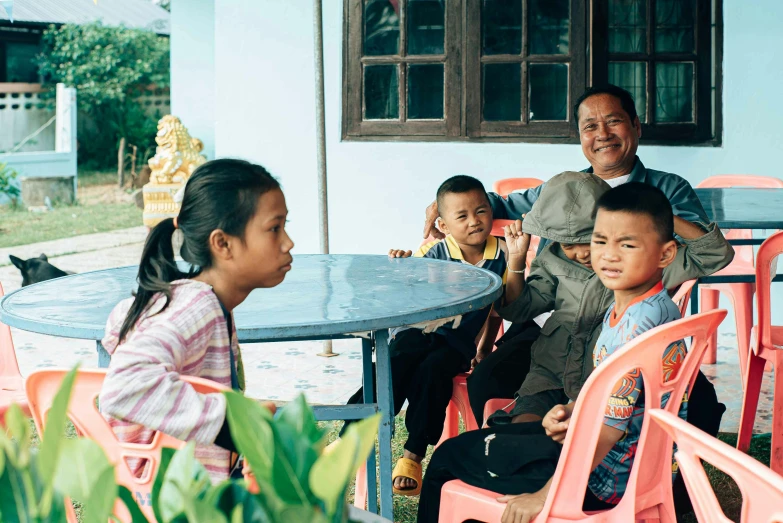 s sit around a round dining table in a village