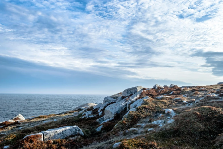 a man walking down a rocky hillside by the ocean