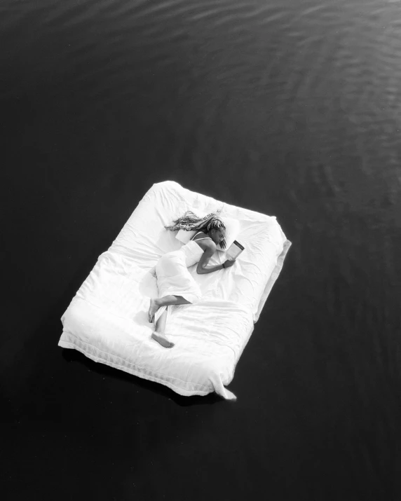 a couple laying on top of a mattress on the water