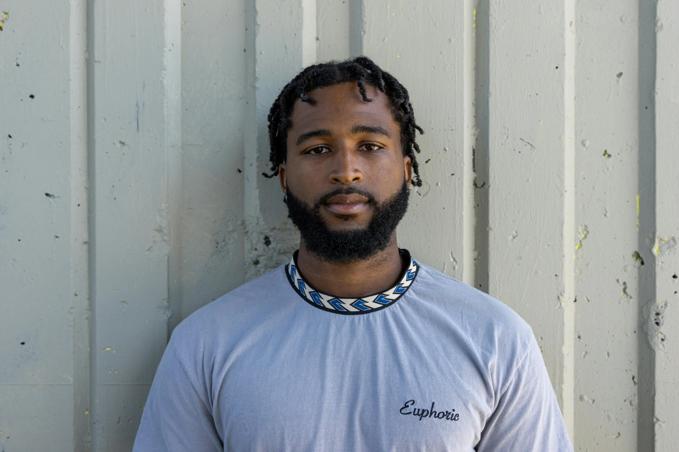 a man in a t - shirt that is standing next to a wall