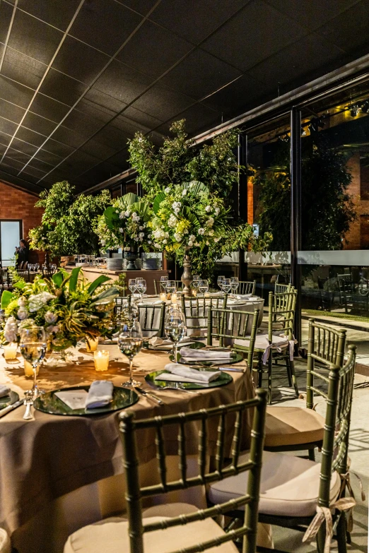 tables set up for a dinner or reception with greenery