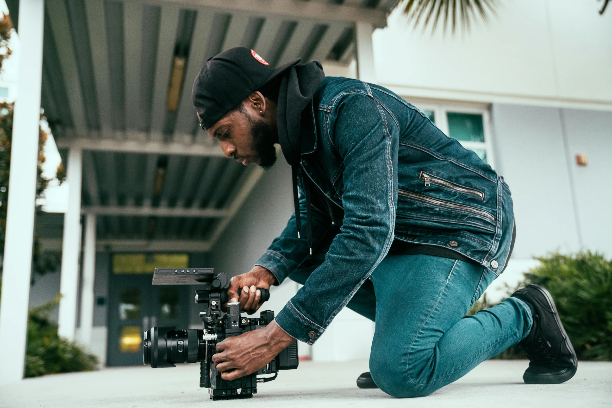 a man kneeling down holding a camera and looking at it