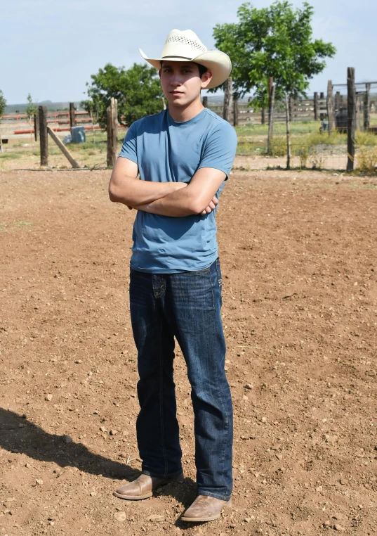 a young man is wearing a cowboy hat while standing in an open field