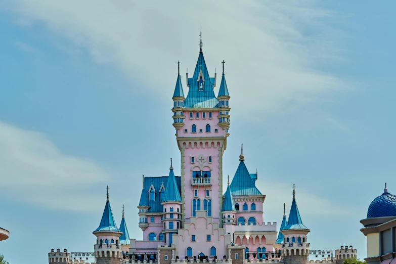 a blue and pink castle sitting next to a giant building